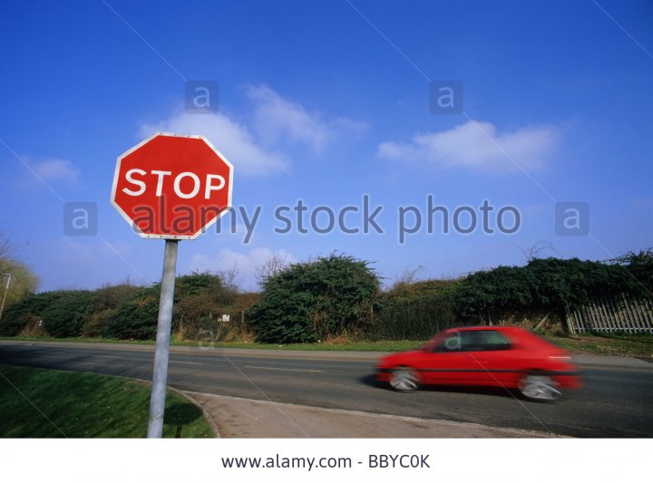 car-and-lorry-passing-stop-sign-at-road-junction-near-leeds-yorkshire-BBYC0K.